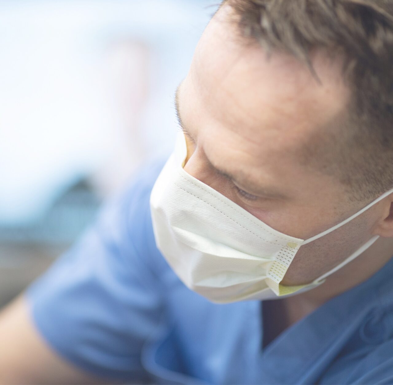 Close-up of Dr Ben while he's working in a medical mask and blue scrubs.