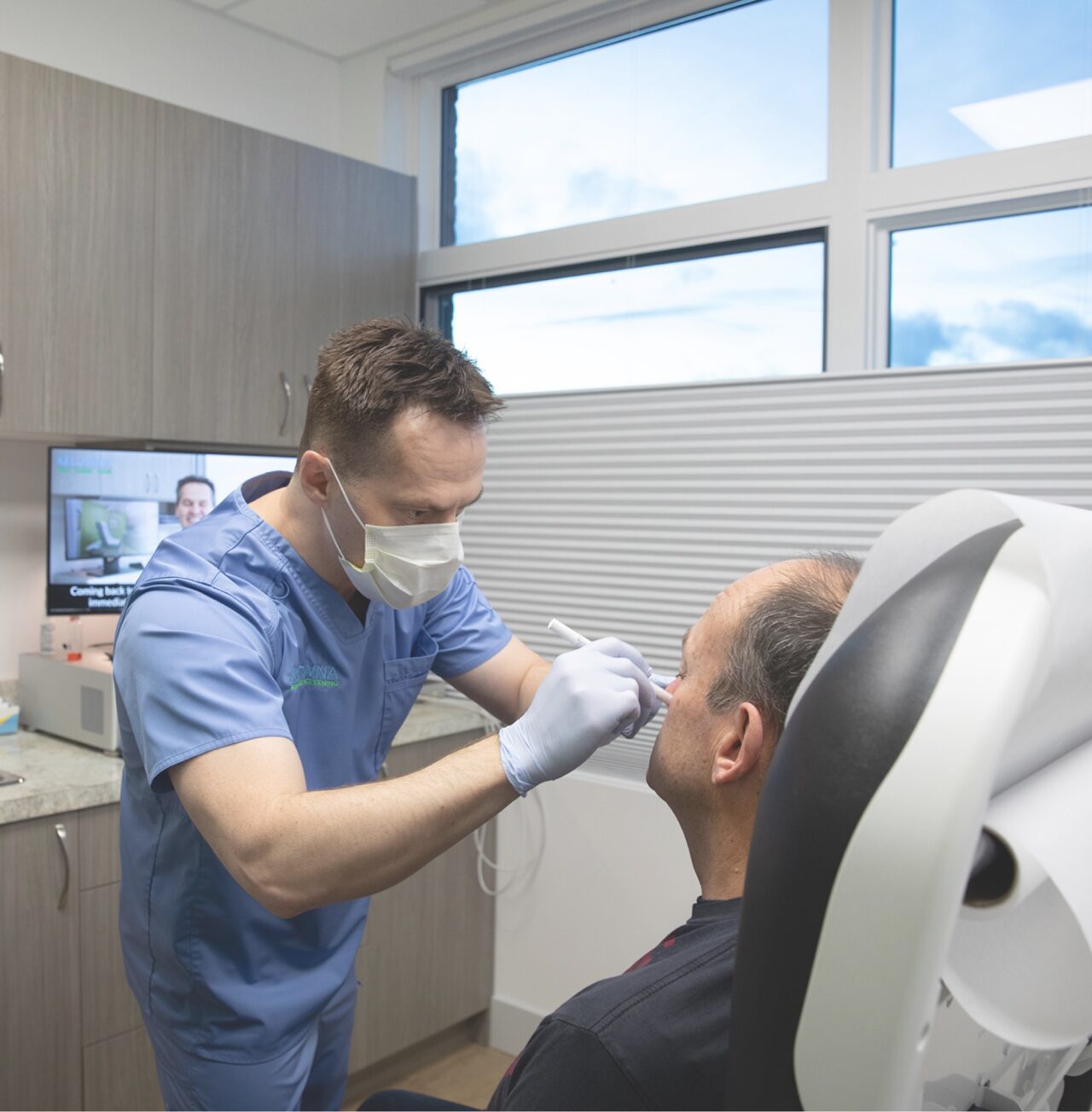 Picture of Dr Ben, a doctor, in his office examining a patient for skin cancer. 