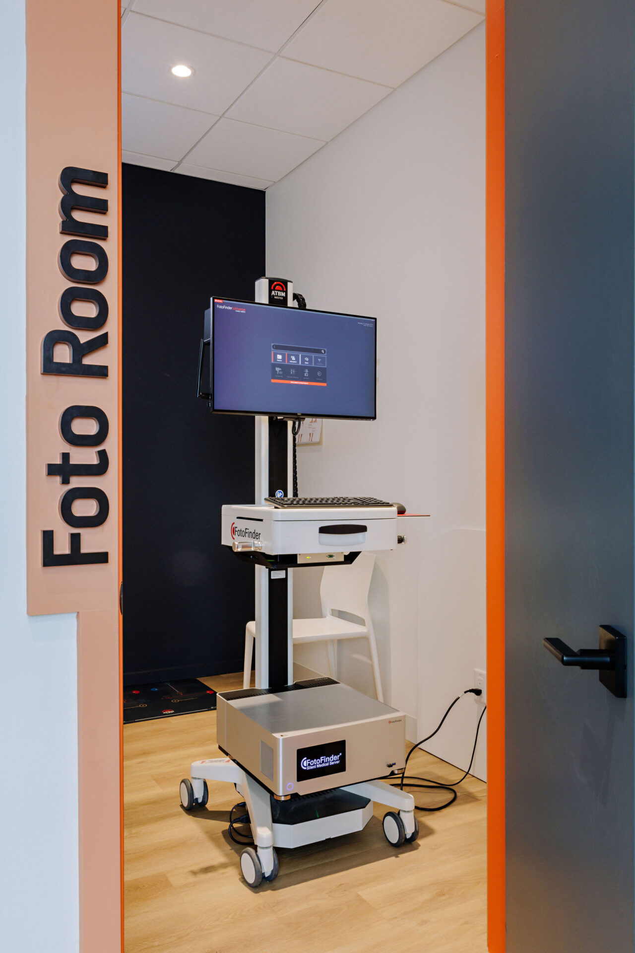 A Foto Finder machine in a small room with wooden floors and grey walls.